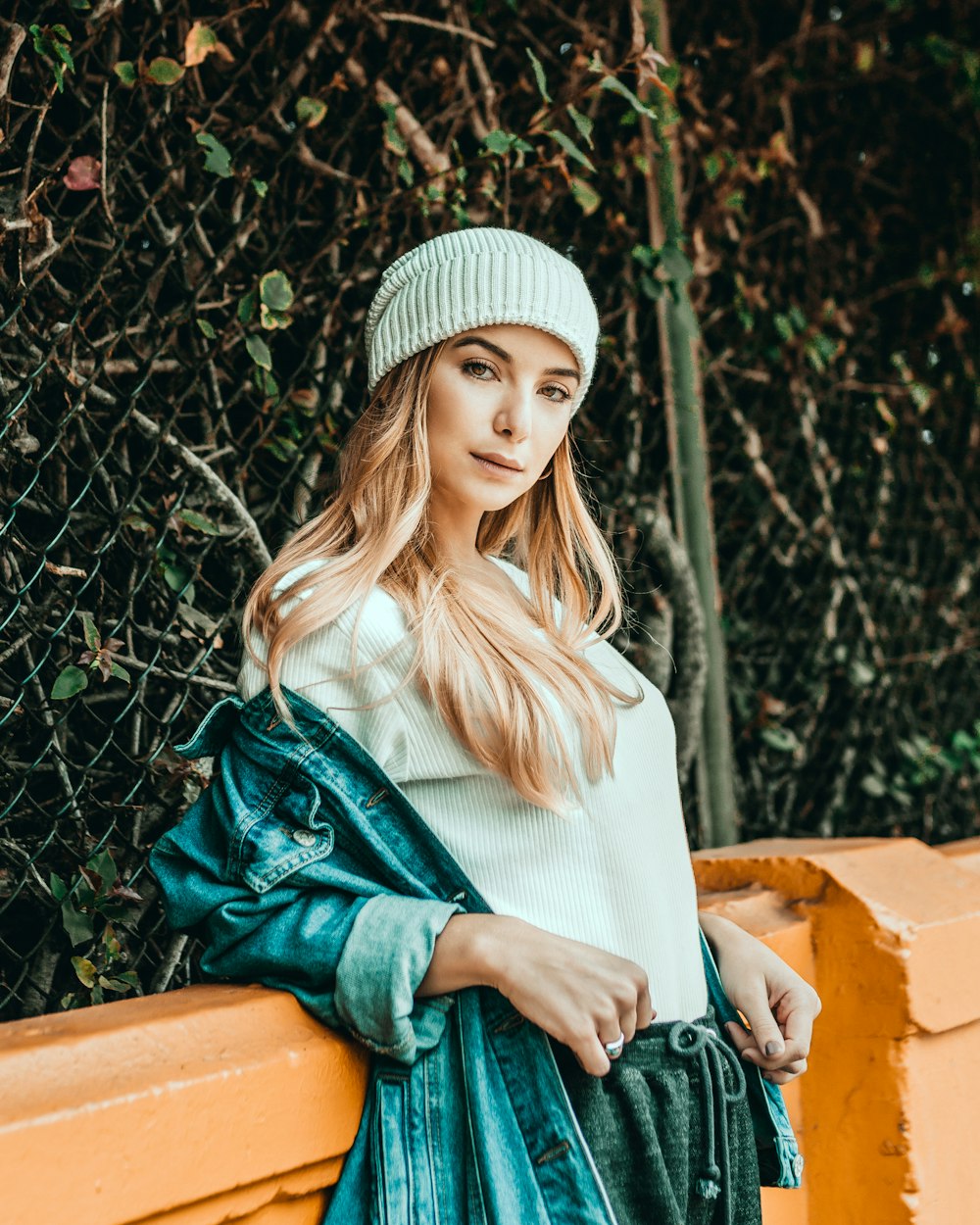 woman leaning on orange fence while looking straight to the camera