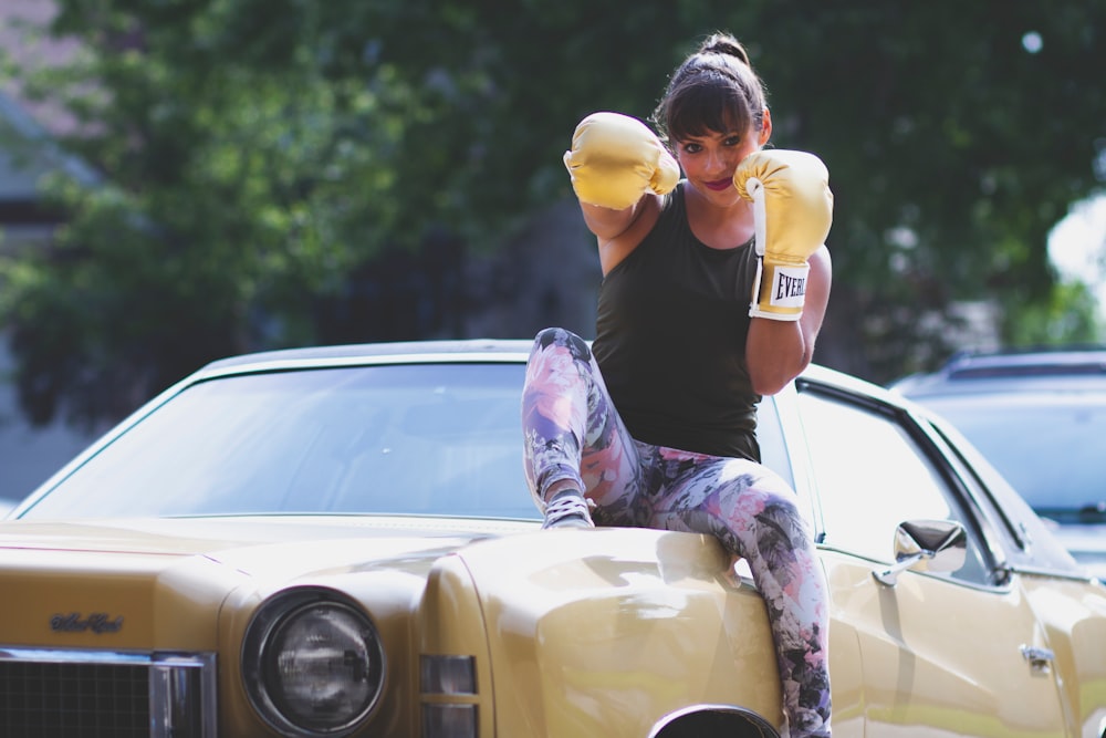 woman sitting on yellow car while punching air
