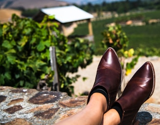 A pair of polished leather boots resting on a stone floor with natural sunlight.