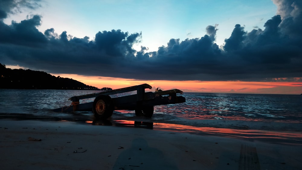 flatbed trailer left on seashore under dark cloudy sky