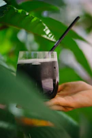 A hand holding a fresh green juice glass with condensation.