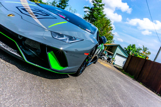 A sleek anthracite golfrider vehicle with neon green accents parked on a lush golf course under a clear sky.