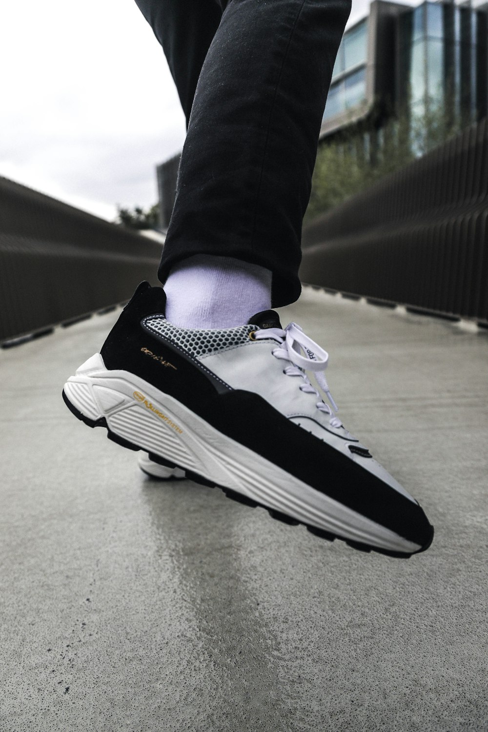 person running on concrete surface wearing white-and-black running shoes