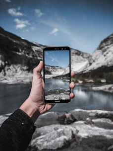 A traveler happily booking a trip on a smartphone with a scenic mountain backdrop.