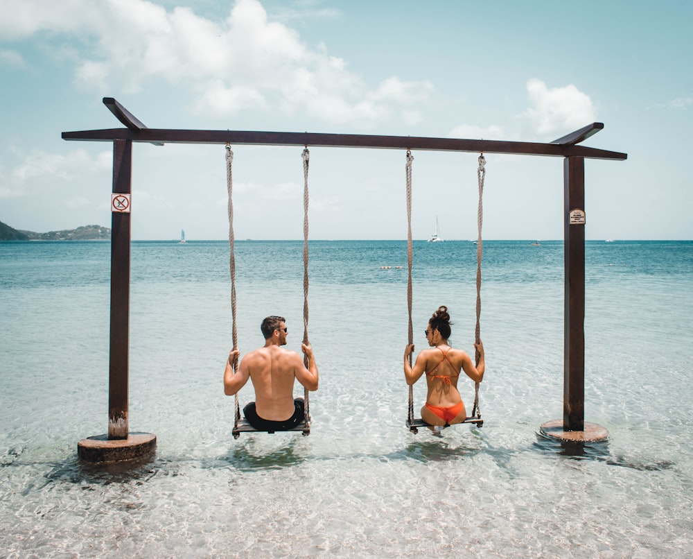 man and woman on swing on body of water