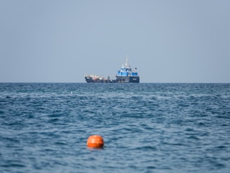 A large tanker ship navigating calm blue waters under a clear sky, loaded with petroleum products.