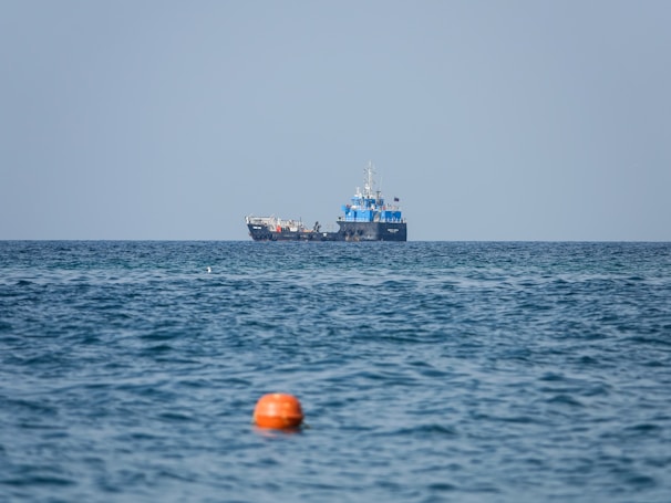 A large tanker ship navigating calm blue waters under a clear sky, loaded with petroleum products.