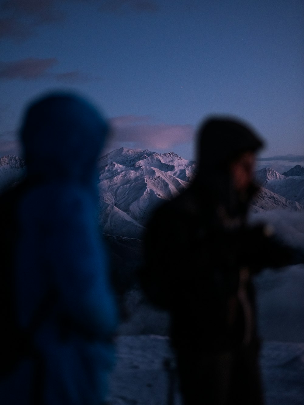 a couple of people standing on top of a snow covered slope