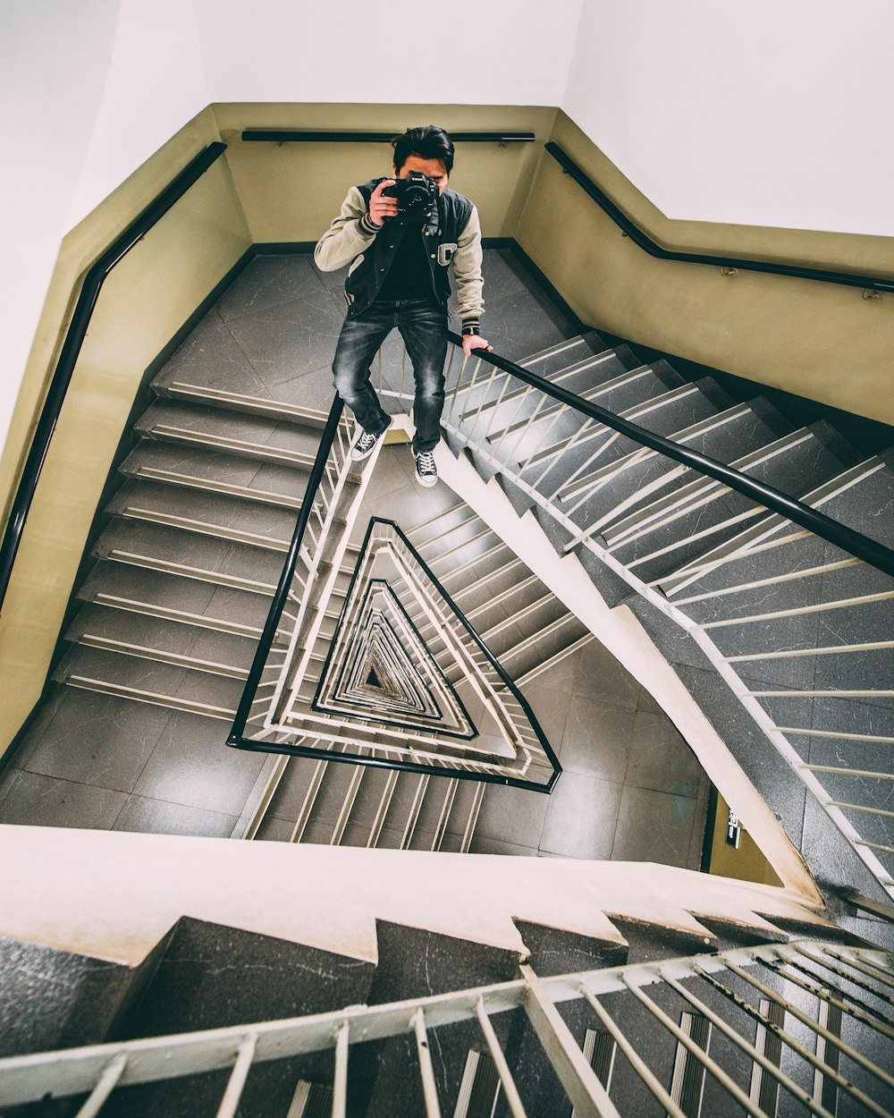 man sitting on stair rail holding DSLR camera