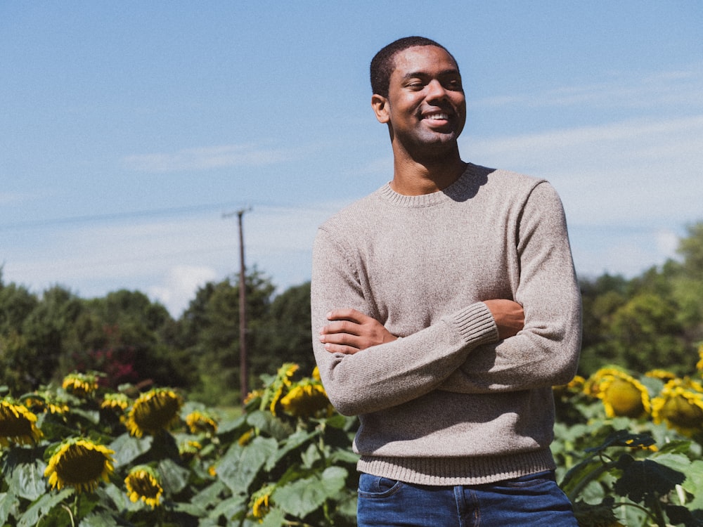 man smiling while taking photo near the sunflower