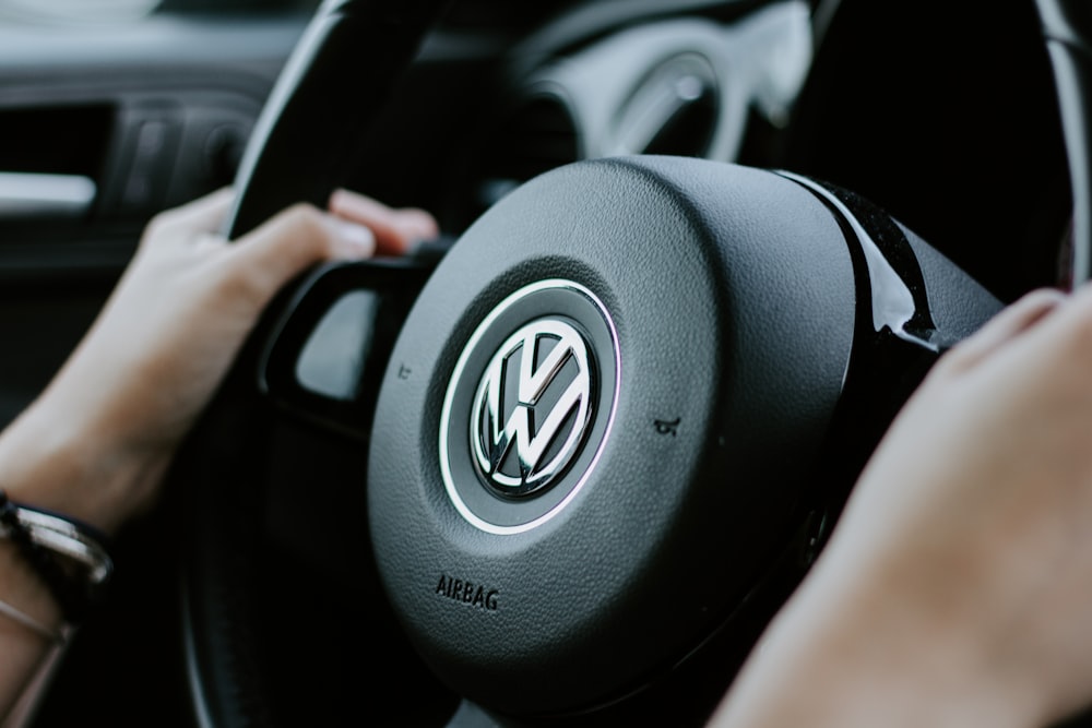 Person mit schwarzem VW-Lenkrad auf geschlossenem Foto