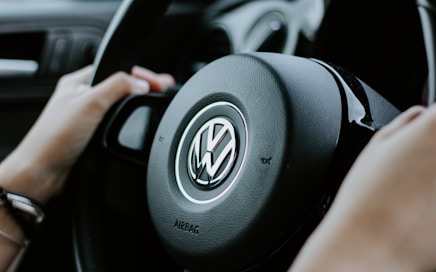 person holding black Volkswagen steering wheel in closed-up photo