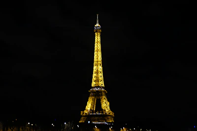 The iconic Eiffel Tower glowing at dusk with Parisian city lights twinkling below.