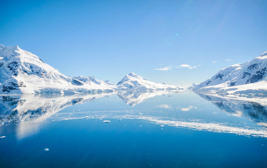 mountain with snow near body of water