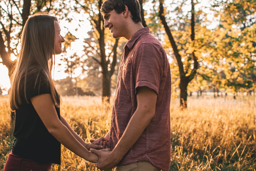 man and woman holding hands while looking at each other