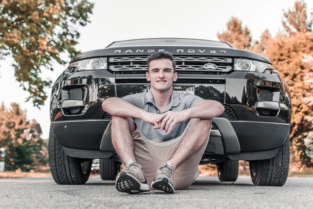 homem vestindo camisa polo cinza na frente do carro Range Rover