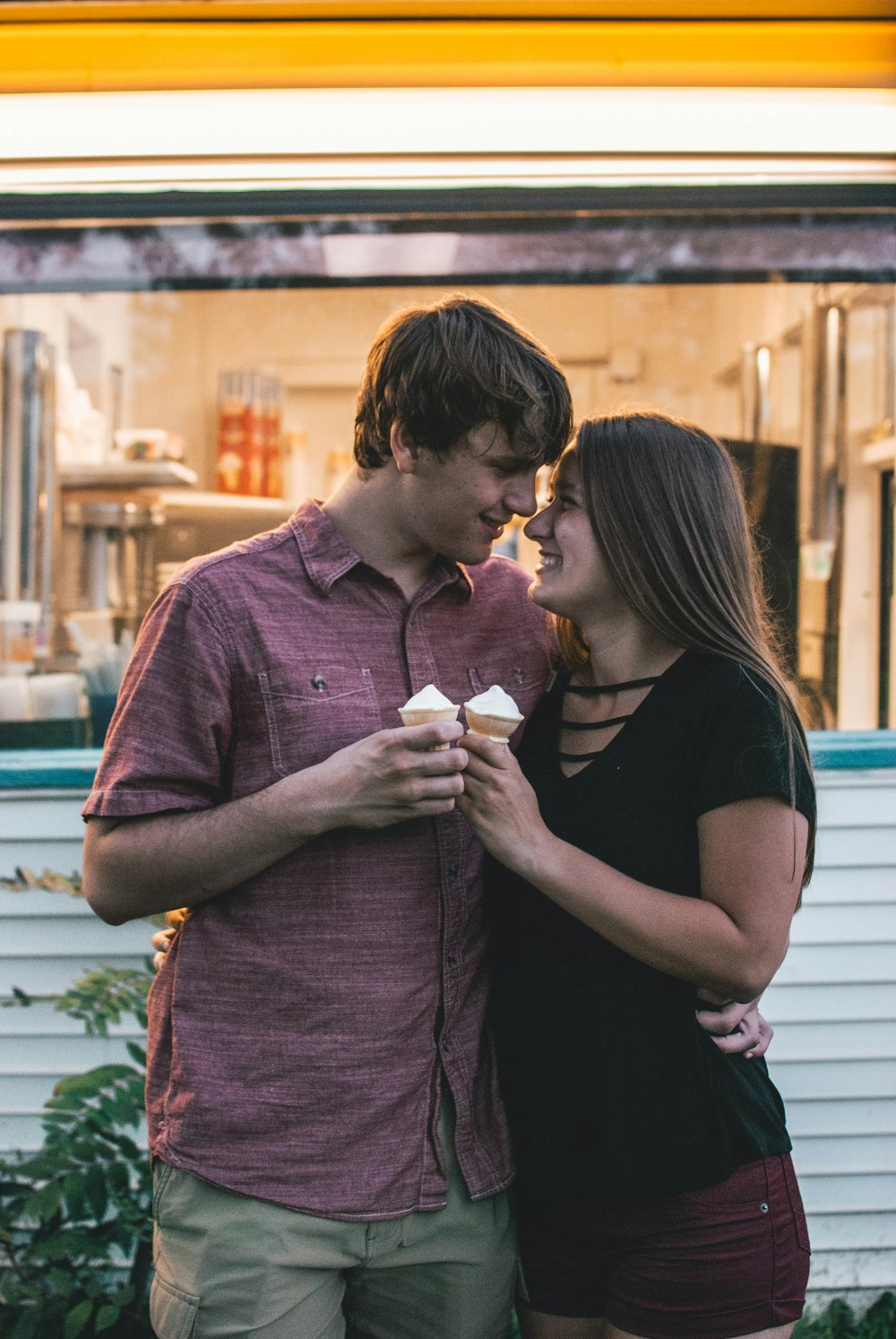 man hugging woman while holding ice cream