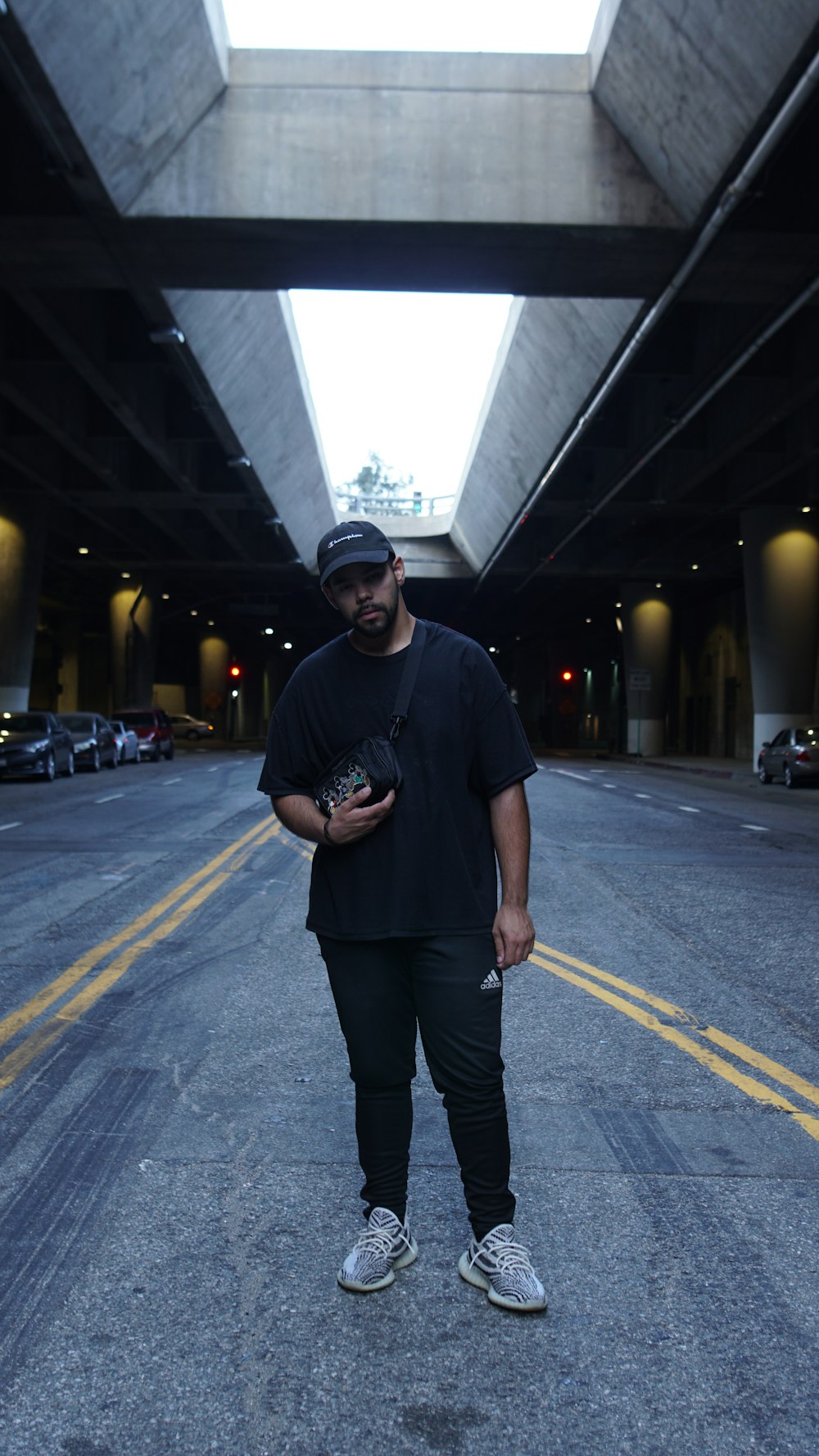 man in black crew neck t-shirt and black pants standing on gray asphalt road during