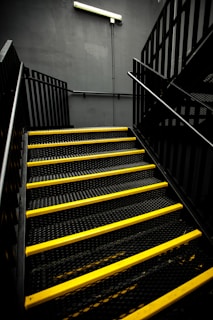 Close-up of a yellow anti-slip stair cover installed on a metal staircase in an industrial plant.