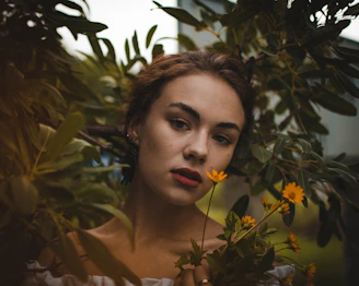 A serene woman surrounded by soft beige and deep green tones, embodying calm confidence and natural elegance.
