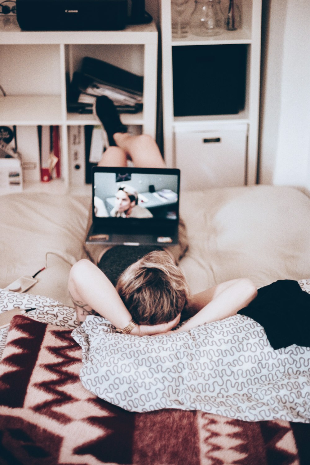 femme allongée sur son lit tout en regardant la télévision