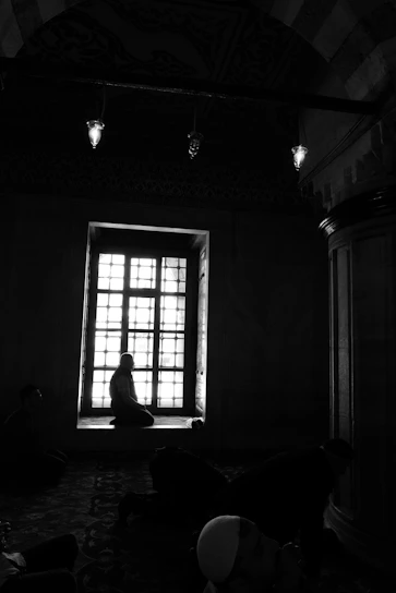A warm, softly lit image of women praying together in a serene, sunlit room.