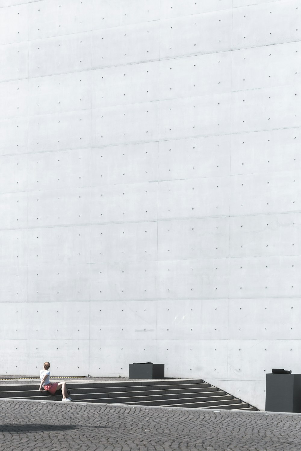 man sitting on gray concrete stairs during daytime