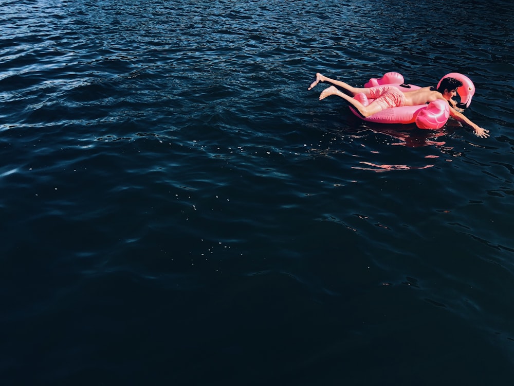 person on pink floater floating on sea