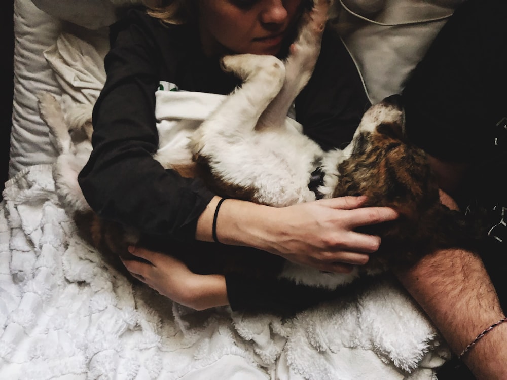 a person laying on a bed holding a dog