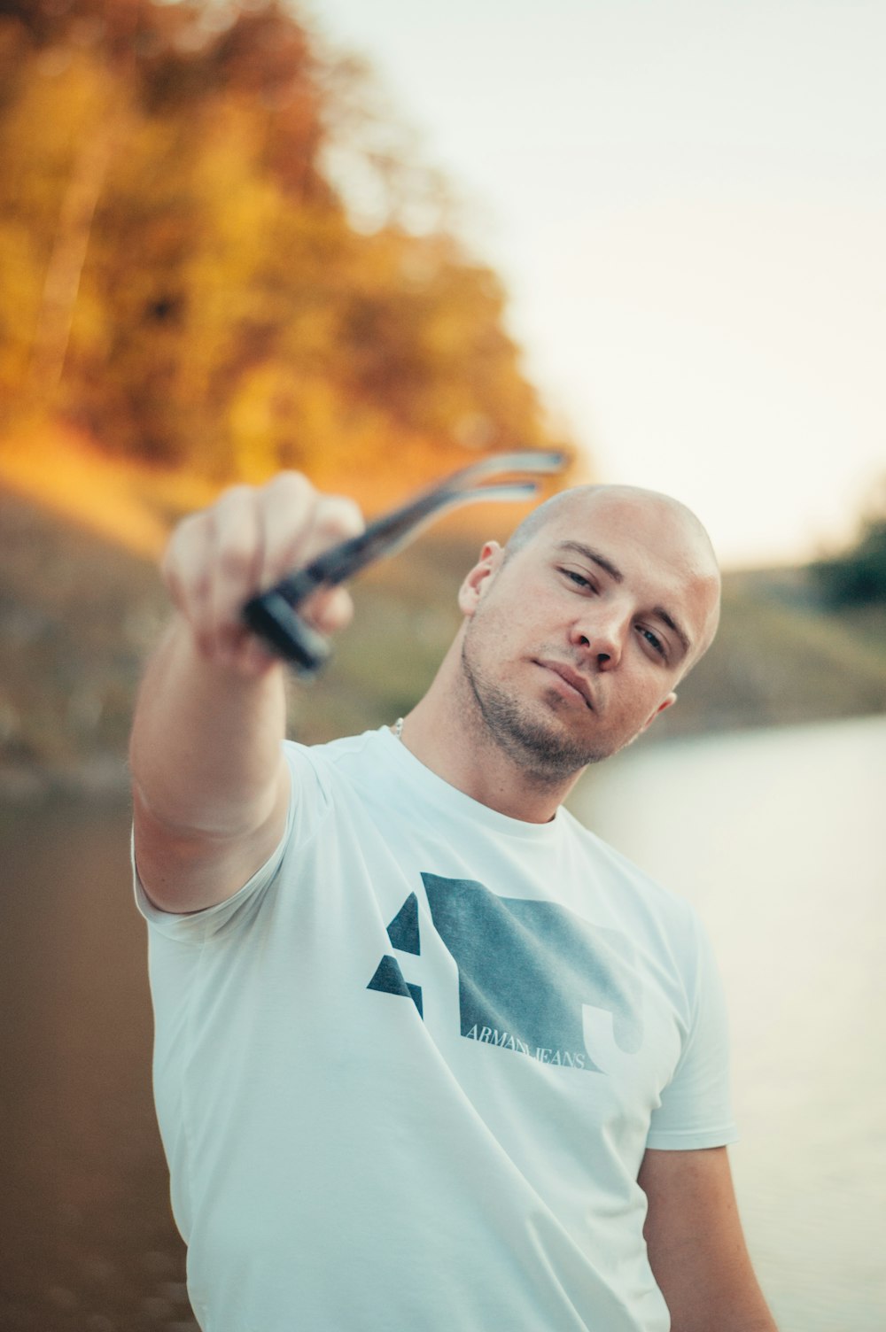 man in white crew-neck T-shirt holding sunglasses