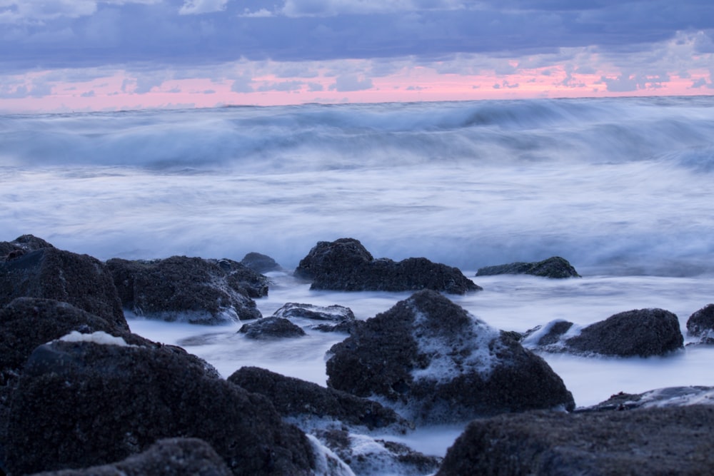 black rocks on sea at daytime