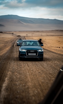 Audi Q7 in metallic gray cruising on a scenic mountain road at sunset.