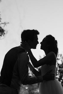 silhouette grayscale photo of man and woman attempting to kiss