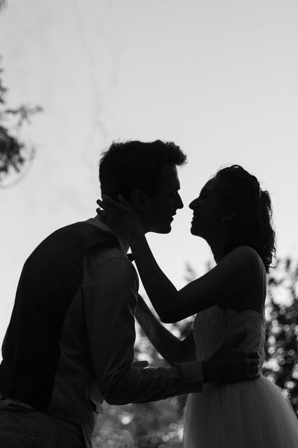 silhouette foto in scala di grigi di uomo e donna che tentano di baciarsi
