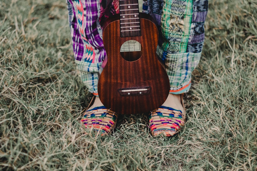 ukulele marrom nos pés da pessoa