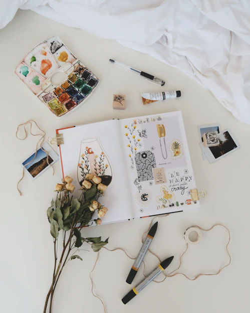 A bright, playful flat lay of colorful customizable t-shirts with art supplies and design sketches around.