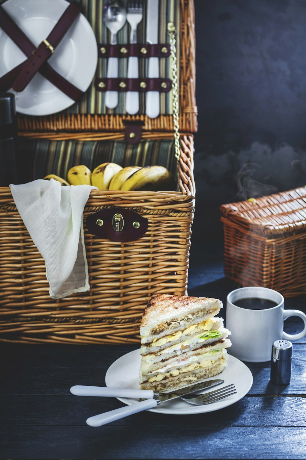 Sandwich auf Teller neben braunem Weidenkorb