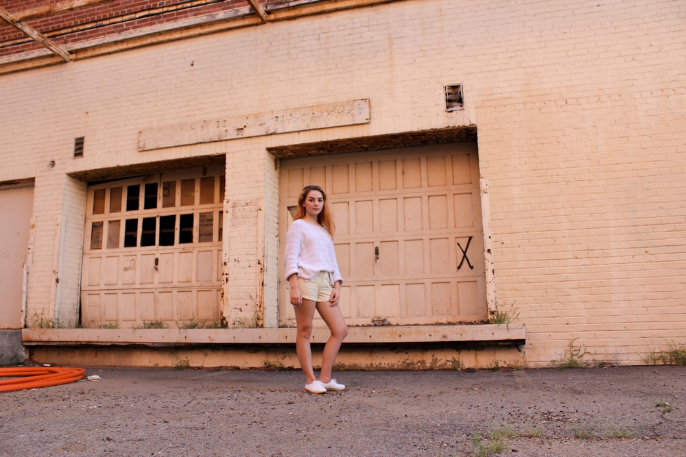 woman standing behind orange painted building