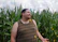 A joyful traveler participating in a traditional corn workshop, surrounded by vibrant native maize plants.