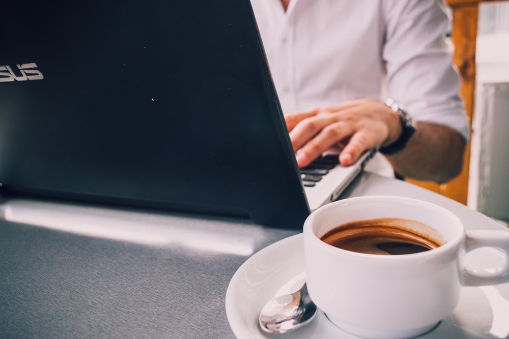 laptop beside mug on table