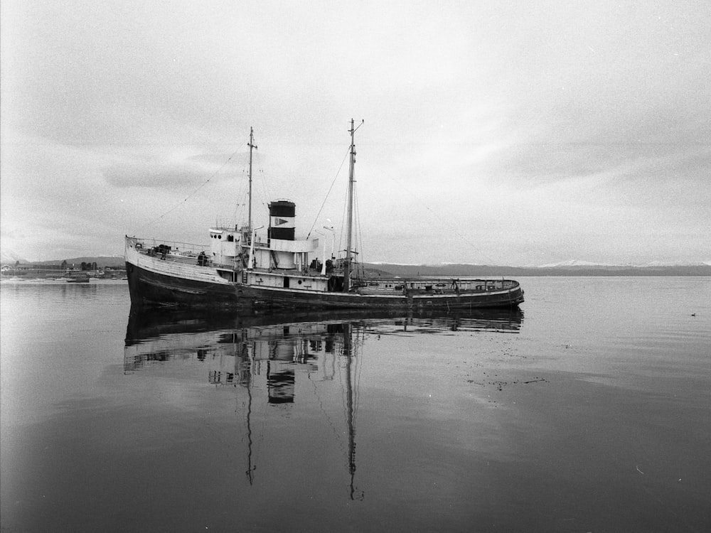 foto em tons de cinza do navio de pesca no corpo de água