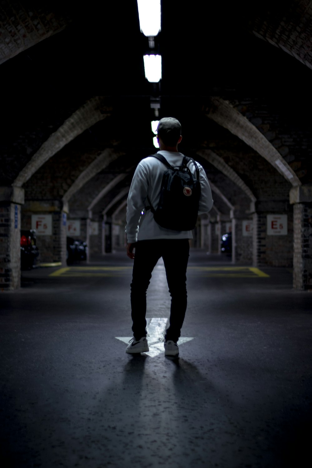 man in black and white jacket and black pants walking on tunnel