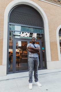 Small business owner proudly standing in front of their storefront.