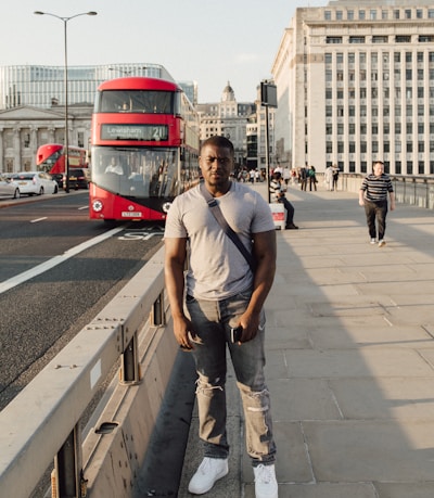 man standing beside railings and asphalt road