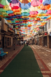 assorted-color umbrella covering alley during daytime