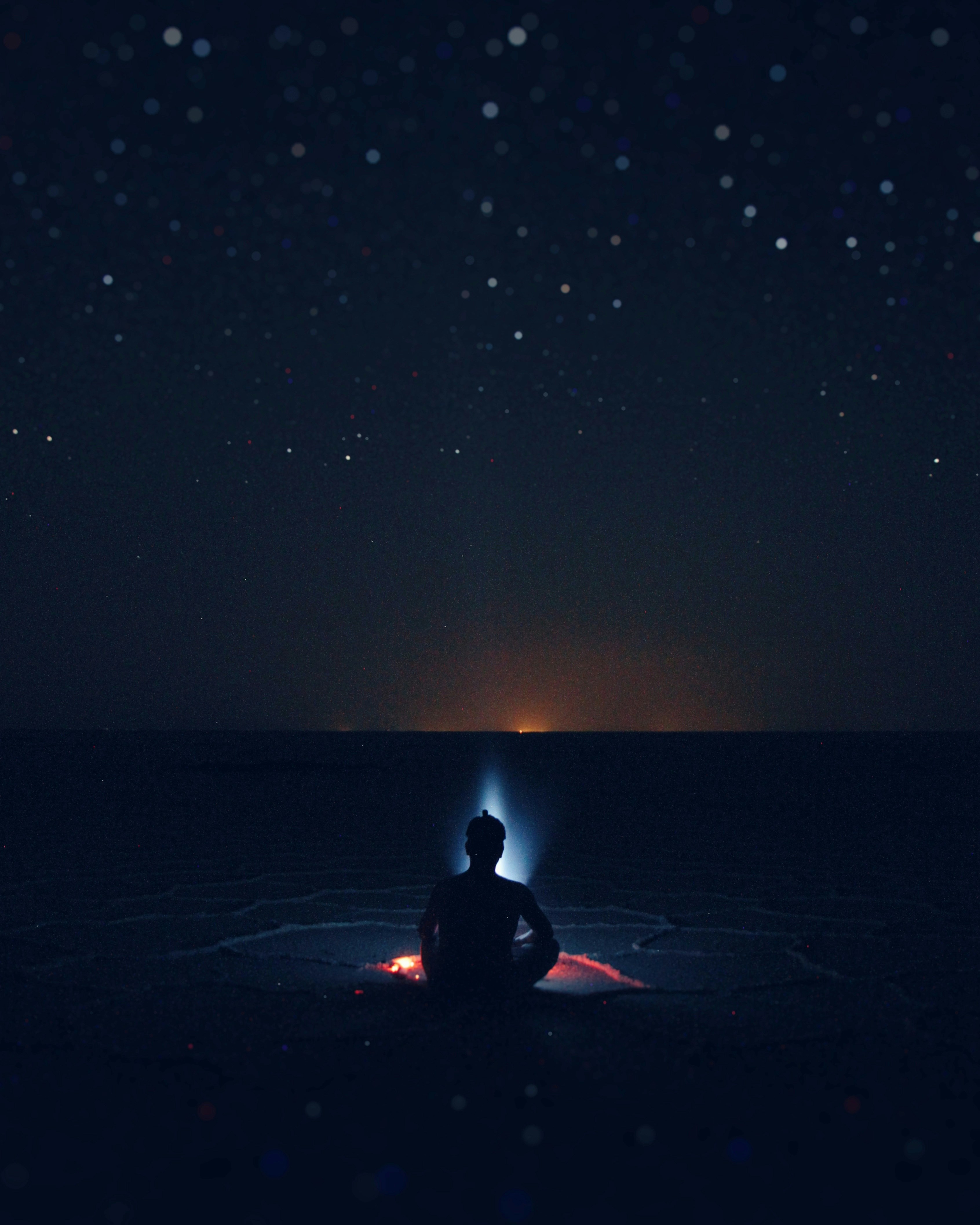 silhouette of person sitting on shore beside bonfire digital painting