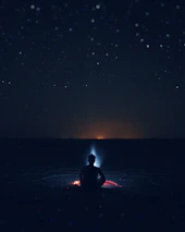 A peaceful meditation scene with a person sitting cross-legged under a starry cosmic sky, third eye illuminated.