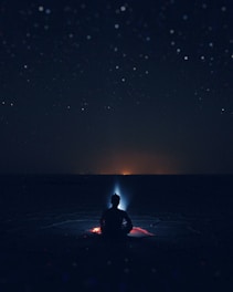 A serene landscape with a person meditating under a starry sky, symbolizing spiritual awakening.