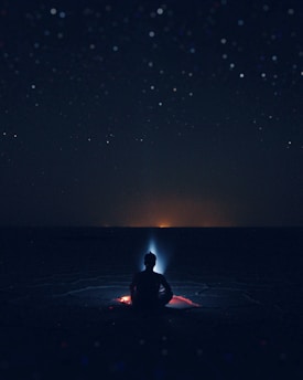 A serene figure meditating under a glowing cosmic sky filled with stars and subtle energy waves.