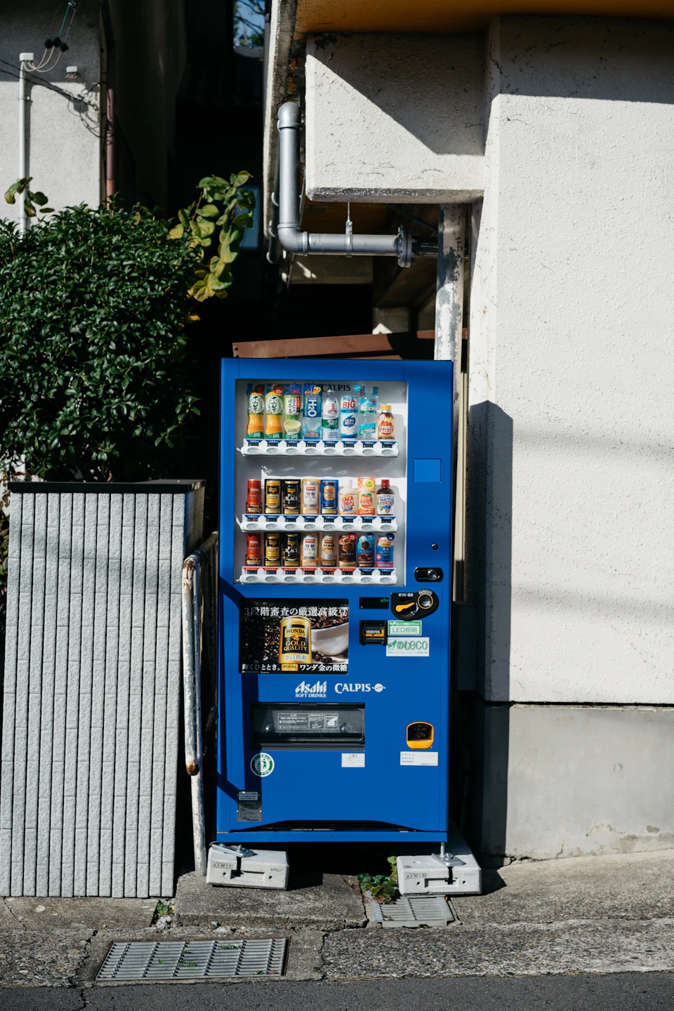 Blue Japanese beverage vending machine with rows of hot and cold canned coffee marked by red and blue price tags